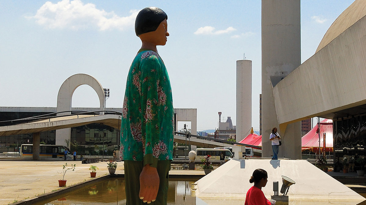 A boneco gigante (giant puppet) walks behind a woman in Santa Cecilia, São Paulo, Brazil. Photo © Renato Targa.