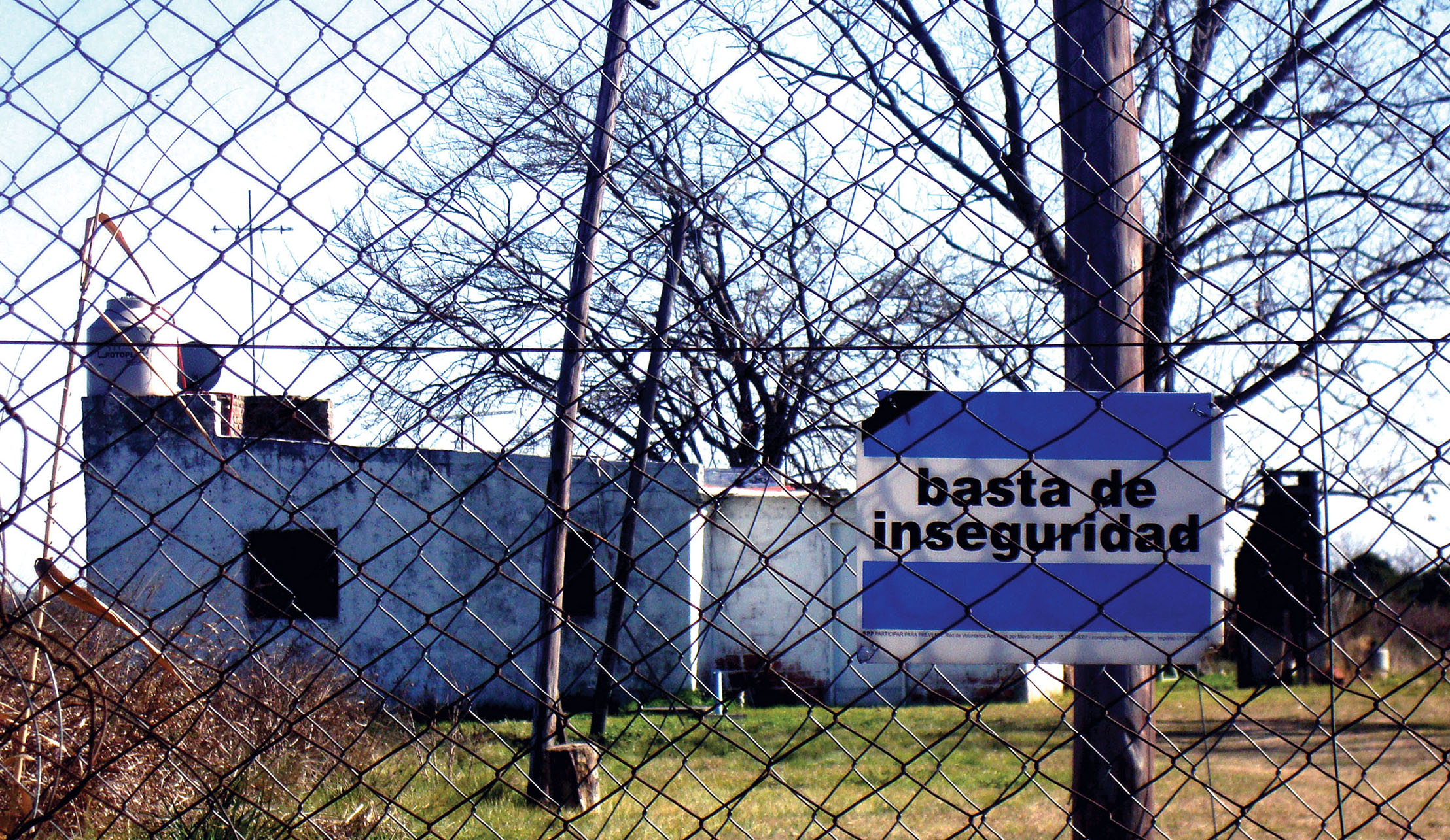 A sign reading “enough insecurity” over the form of the Argentine flag hangs from a tall fence. (Photo by Asa Perry.)
