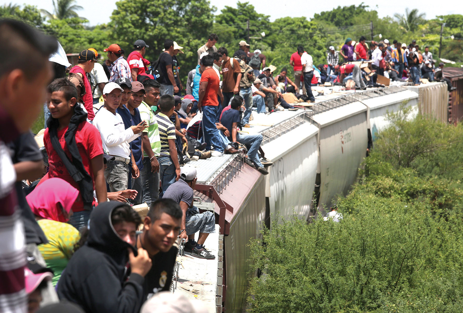 Migrants pass through Ixtepec, Mexico, riding in the open atop freight cars of a train known as “la bestia.” (Photo by John Moore/Getty Images.)