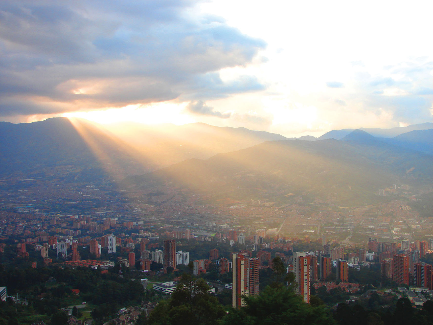 Beams of light illuminate the city as the sun breaks through the clouds over Medellín, Colombia. (Photo by Iván Jere Jota.)