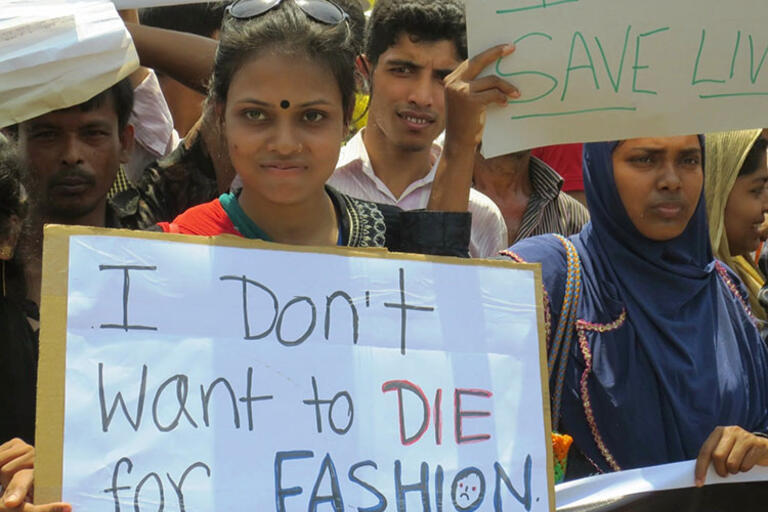 (Photo by Solidarity Center/Sifat Sharmin Amita.) A woman from India holding a sign that reads "I don't want to die for fashion"