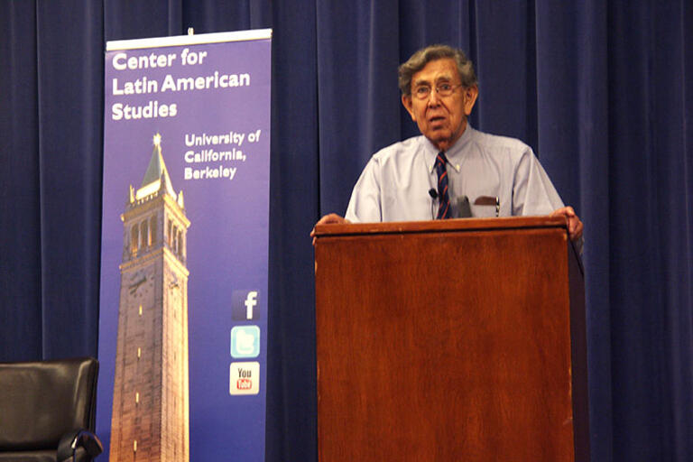 Cuauhtémoc Cárdenas speaking at UC Berkeley, standing in front of a CLAS banner
