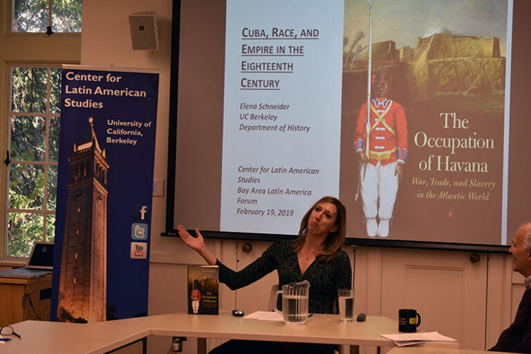 Elena Schneider starts off her presentation talking about her book, seating with both her hands up