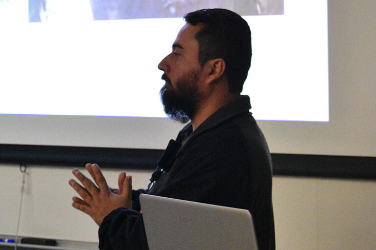 Diaz goes over a video that explains the basic details of the massacre. (Photo by Julia Byrd.) Alejandro Díaz standing up and talking with his hands up