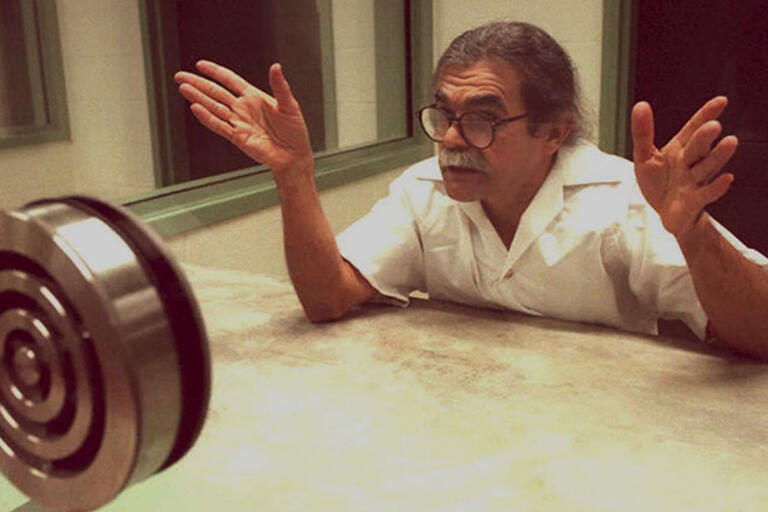 Oscar López Rivera being interviewed before his release from prison. (Photo courtesy of Democracy Now.) Oscar López Rivera behind a glass being interviewed before his release from prison