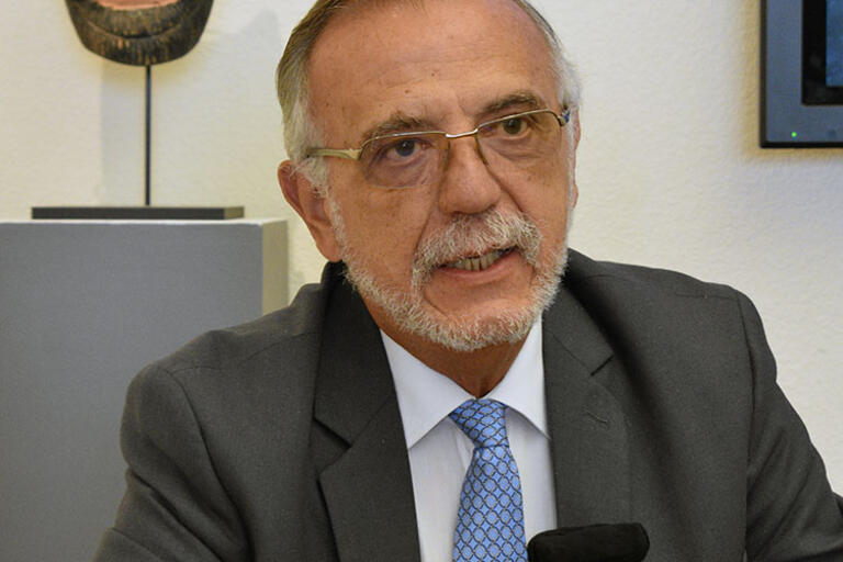 Iván Velásquez Gómez describes his experiences as the leader of CICIG. (Photo by Julia Byrd.) Iván Velásquez Gómez seating speaking with a mask behind him