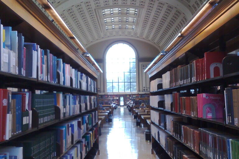 Aisle in a library with books on the side and window at the end