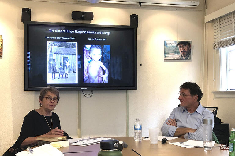 Nancy Scheper-Hughes and Walter Belik seating in a table discussing hunger in Brazil and the U.S.