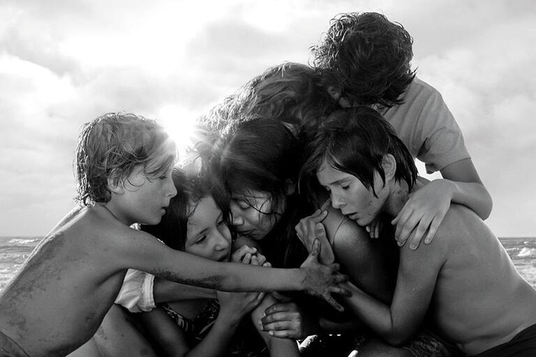 Still from Roma. A group of children hug in a pile at the beach