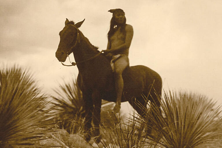 An Apache scout on horseback surveys the countryside. (Photo by Edward S. Curtis.)
