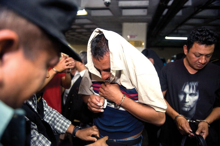 Guatemalan police officers accused of kidnapping, robbery, and abuse of authority head to court with their faces hidden. (Photo by Johan Ordoñez/Getty Images.)