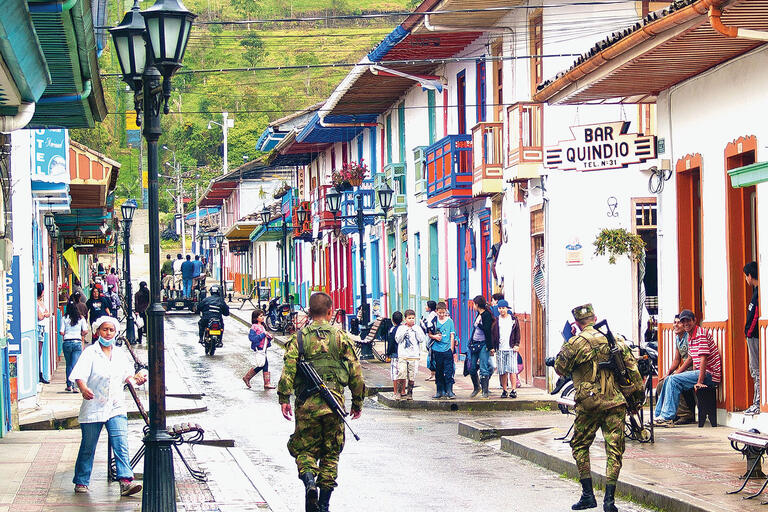 Armed soldiers walk down a street with colorful houses and balconies in Salento, Colombia. (Photo by Gonzalo G. Useta.)