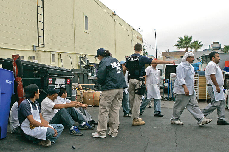 Immigration agents detain employees of San Diego’s French Gourmet Restaurant  in a raid that led to felony indictments against the restaurant’s owner and manager. (Photo by Lenny Ignelzi/Associated Press.)