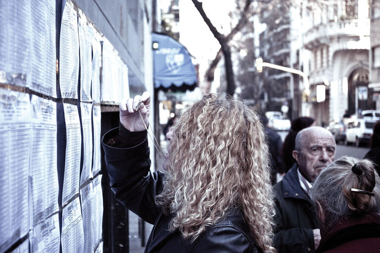 An Argentine woman looks for her name on the voting rolls posted on a wall in Argentina. (Photo by Gustavo Facci.)