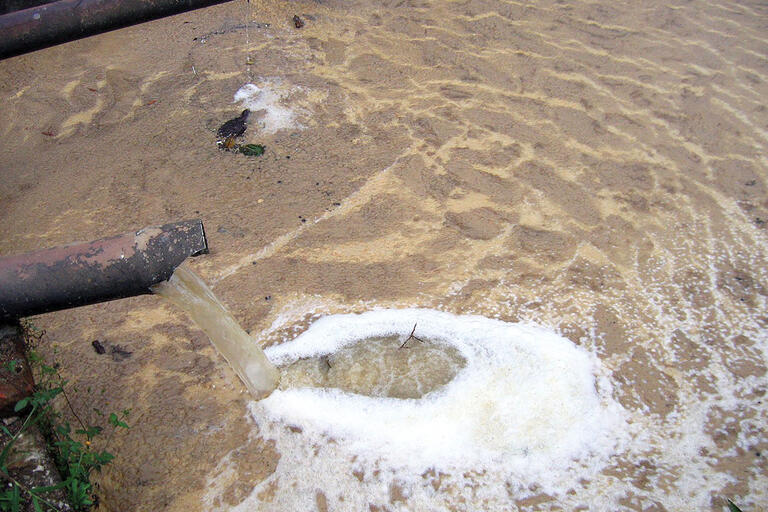 Contaminated water pours from a pipe in Nicaragua. (Photo by Ben Garland.) Contaminated water pours from a pipe into a brown, foaming pool in Nicaragua. (Photo by Ben Garland.)