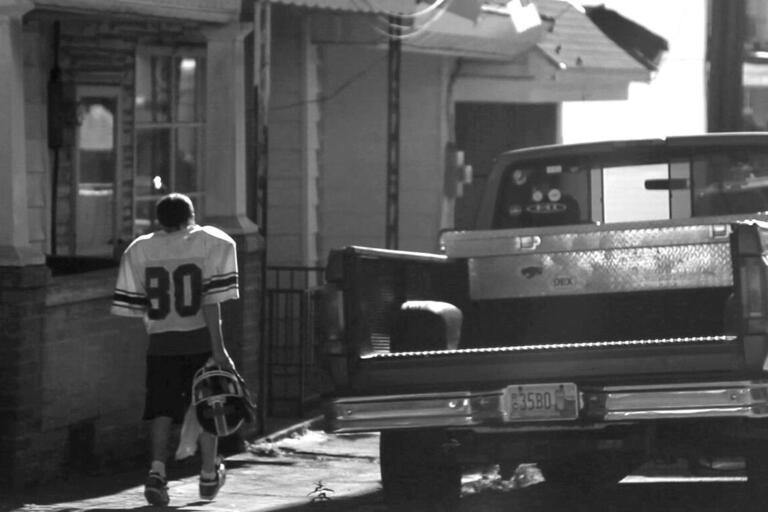 A teenager in a football uniform walks down the street in Shenandoah. (Photo by and © David Turnley.)