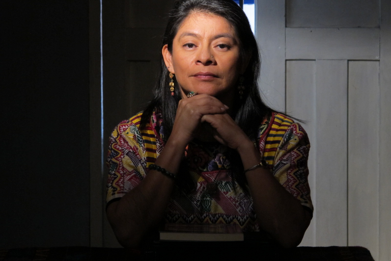 Irma Alicia Velasquez Nimatuj. A woman stares intently at the camera with hands folded.