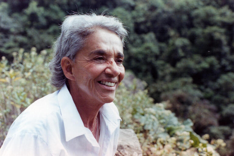 Still from "Chavela." A woman sits in front of greenery