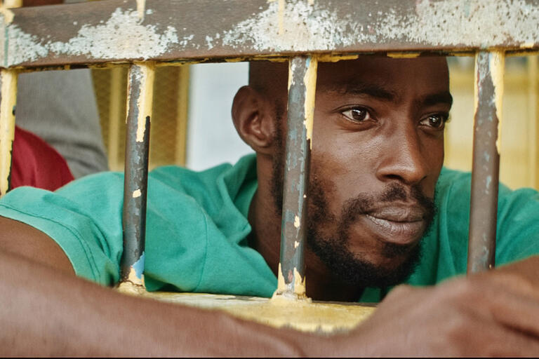 A man looks through bars.