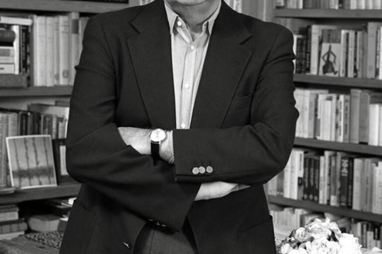 Octavio Paz in 1984. A man stands with folded arms in front of bookshelves