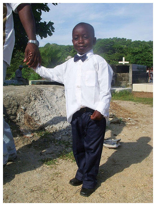 Junior Alexander in a white shirt and bow tie at his father’s funeral. (Photo courtesy of 72migrantes.com.)