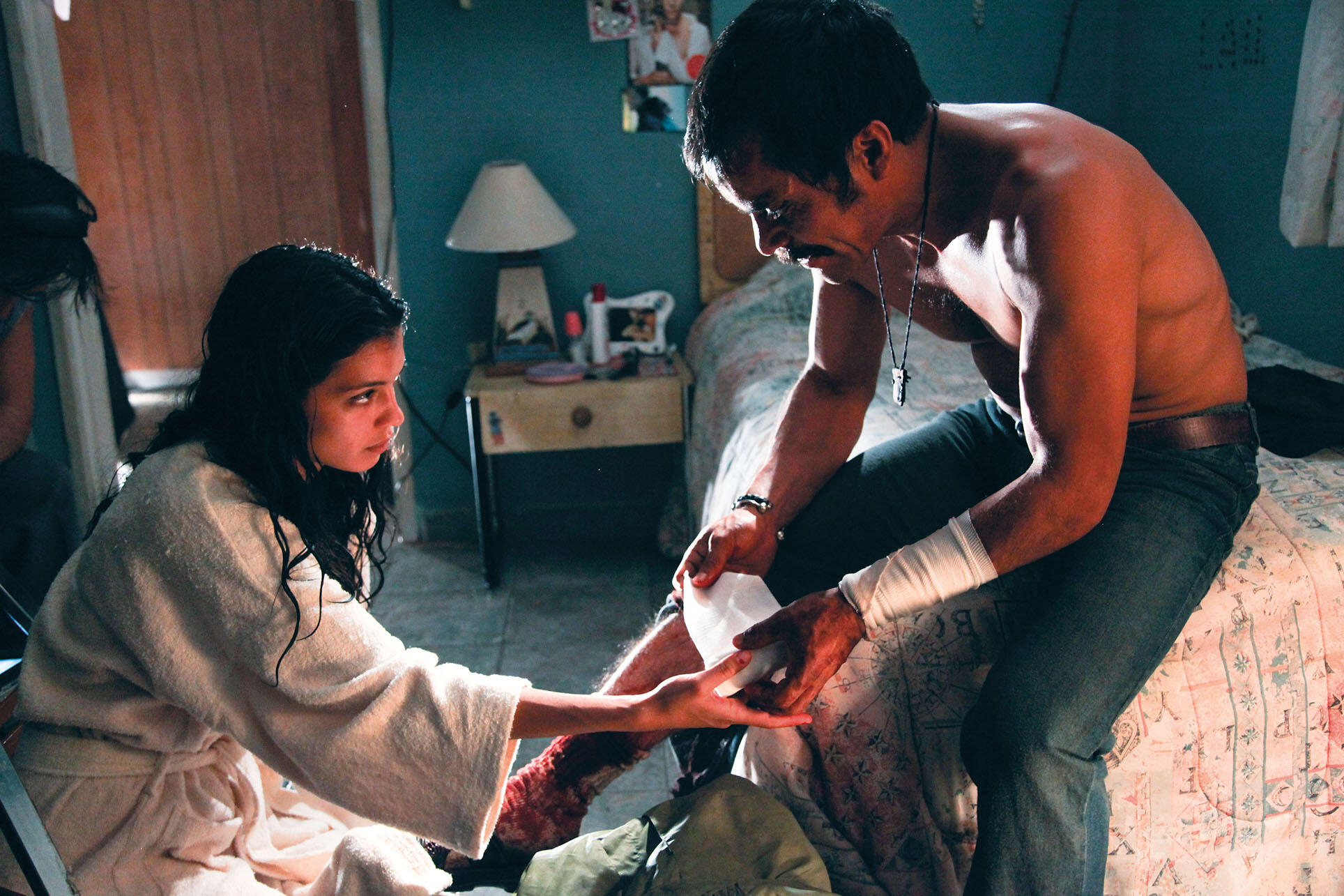 Stephanie Sigman as the lead character numbly helps her drug kingpin tormentor bandage wounds from a gunfight. (Image courtesy of Canana Productions.)