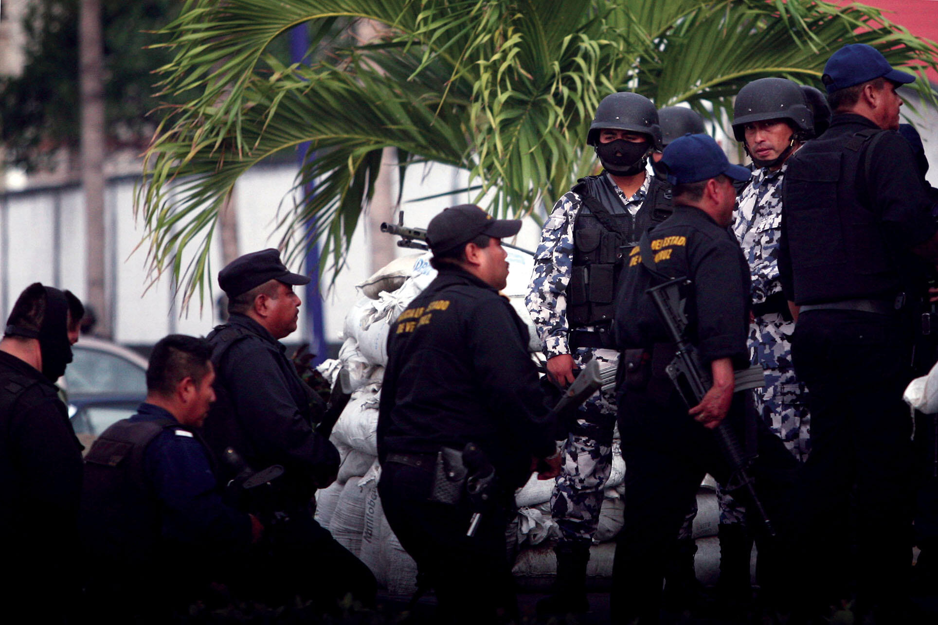 Formers officers walk past Mexican marines, who took over policing in the city of  Veracruz after the entire police force was disbanded in an attempt to root out corruption. (Photo by Felix Marquez, Associated Press.)