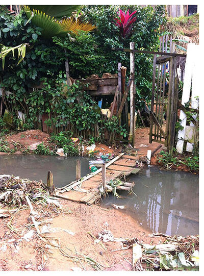 A makeshift bridge crosses an open sewer in the Pau da Lima favela in Salvador, Brazil. (Photo by Guillermo Jaimes.)